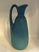 Front side view of the turquoise ceramic vase with handle, showing its smooth matte finish and slender form.