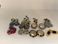 Full view of nine pairs of vintage clip-on earrings showing variety in color and design.