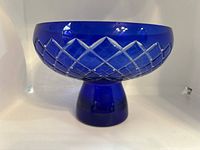 Side angle showing the cobalt blue glass vase with clear cut lattice pattern and pedestal base.