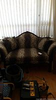 Front view of wooden sofa with leopard print upholstery and cushions, showing full seating area and general condition.