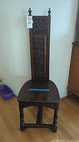Full view of antique Scottish hall chair showing tall carved back and solid wood seat.