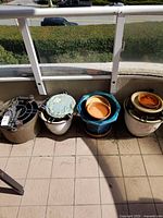 Four assorted planters lined up on balcony floor showing different styles and bases