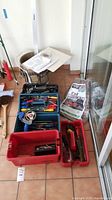 Full view of assorted hand tools including multiple tool boxes, bucket, tarp, and drywall patches; showing screwdrivers and other hand tools inside the boxes.