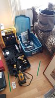 Overview showing DeWalt compressor, drill case with charger and battery, blue bin with biscuit joiner and nail tool boxes, and Lee Valley canvas bucket.