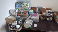 Overview of lot showing multiple boxes and items spread on table including light bulbs, power bars, and switches