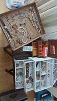 Overhead shot of entire lot: assorted jewelry, two wooden jewelry boxes and eye loupes box