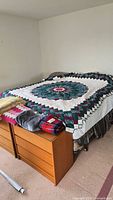 Full view of two king size quilts on bed with folded blankets at foot
