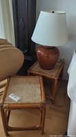 Table lamp with brown ceramic base and white lampshade on one bamboo side table