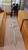 View of floor to ceiling assist pole assembled with base, handle, and ceiling cap around a walker in a room.
