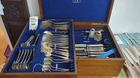 Open wooden flatware chest showing full contents of cutlery and shakers