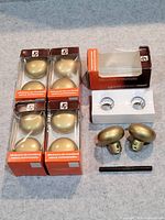 Five sets of Ilco Unican replacement door knobs in original packaging along with loose knobs, knob collars, and spindle bar on a countertop.