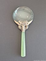 Full magnifying glass showing circular lens, decorative silver mount, and polished jade handle.