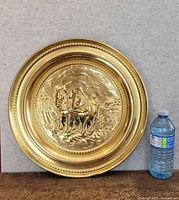 Front view of the large decorative copper plate showing the embossed design of two horses pulling a plow with detailed background and ornate border.