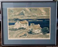Framed serigraph print showing a coastal scene with houses, sea, and distant land. Glass glare visible.