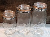 Front view of the three Le Parfaid embossed glass jars with metal clasp seals, arranged by size from smallest to largest.