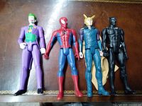 Photo of four collectible action figures: Joker, Spider-Man, Lok-Il, and Black Panther standing upright on a wooden surface.