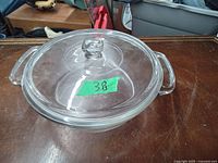 Top view of the clear glass casserole dish with lid on a wooden surface.