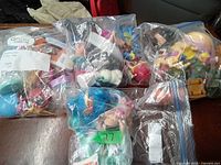 Photo of multiple bagged sets of assorted small toys and figurines on a wooden surface.