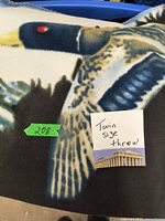 Close up image of a fleece throw blanket depicting a flying duck and a note indicating 'Twin size throw'.