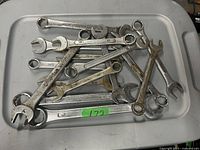 Photo showing about 15 used metal wrenches of various sizes and types piled in a plastic tray.