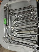 Photo showing 13 combination wrenches of different sizes, arranged on a plastic surface.