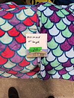 Photo showing two mermaid pattern blankets with a note indicating 4 feet length and good condition.