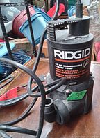 Photo showing close-up front view of the Rigid submersible utility pump, highlighting the label with product details and power cord.