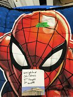 Close-up of the Spider-Man face on the children's weighted blanket with handwritten note showing the size 4ft length by 3ft width and condition described as weighted children's