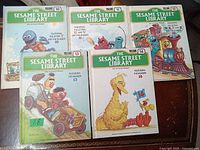 Photo of five colorful hardcover Sesame Street children's books, volumes 10 to 14, shown flat and slightly overlapping, each with illustrated covers featuring well-known Sesame Street characters and volume numbers.