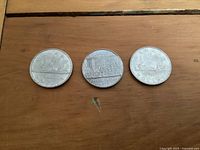 Reverse side of three Canadian one dollar coins showing different designs including loon, cityscape, canoe