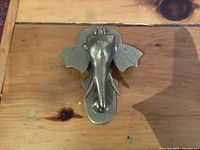 Top view of brass elephant head door knocker showing front detail including trunk, ears and mounting base.