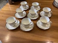 Set of 8 Minton Gloucester cups with matching saucers arranged on wooden surface