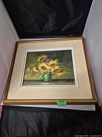 Front view of oil painting featuring sunflowers in a green vase with cream textured mat and wood frame.