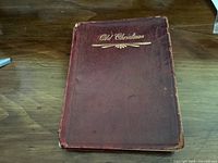 Dark red leather bound book with title 'Old Christmas' embossed in gold on the front cover, showing some wear and edge damage.