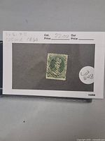 Photo showing a green Nova Scotia postage stamp, Scott #11, postally used from 1860 with visible cancellation marks and perforated edges.