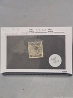 Photo of Prince Edward Island 4 pence black postage stamp from 1868 on a display card showing catalog info and a lot number.
