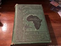 Front cover showing embossed green cloth with title, author, and decorative African map.