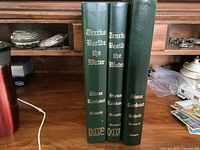Three green hardcover books titled 'Tracks Beside the Water' by Sioux Lookout, Ontario, displayed upright on a wooden desk.