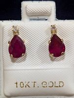 Front view of each earring showing pear-shaped ruby and moissanite stones with 10KT gold setting.