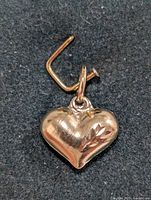 Close-up front view of the 14KT gold heart pendant with a leaf engraving detail on black background.