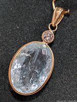 Close-up of the front of the 14KT gold pendant showing the oval faceted aquamarine and round diamond.