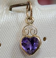 Close-up front view of the heart-shaped amethyst pendant set in 14KT yellow gold with decorative scroll details.