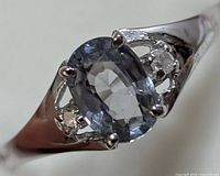 Front-angle close-up of ring displaying oval blue sapphire and side diamonds