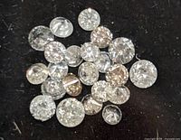 Close-up view of scattered small loose diamonds on a black surface showing various sizes and slight color variations.