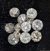 Close-up photo of 11 assorted round brilliant cut diamonds on black background, showing clarity and cut details.
