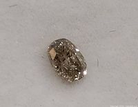 Close-up of oval cut genuine champagne diamond showing facets and pale brown color on a white background.