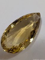 Front view of a large pear-shaped faceted citrine gemstone showing its light golden-yellow color and internal inclusions.