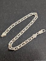 Front view of the silver bracelet laid flat showing link style and clasp.