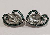 Top view of both pear-shaped green amethyst and gemstone earrings showing intricate silver swirl setting with green stones around main amethyst.