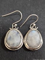 Front view of both earrings showing faceted moonstone set in silver frames, hook wires visible